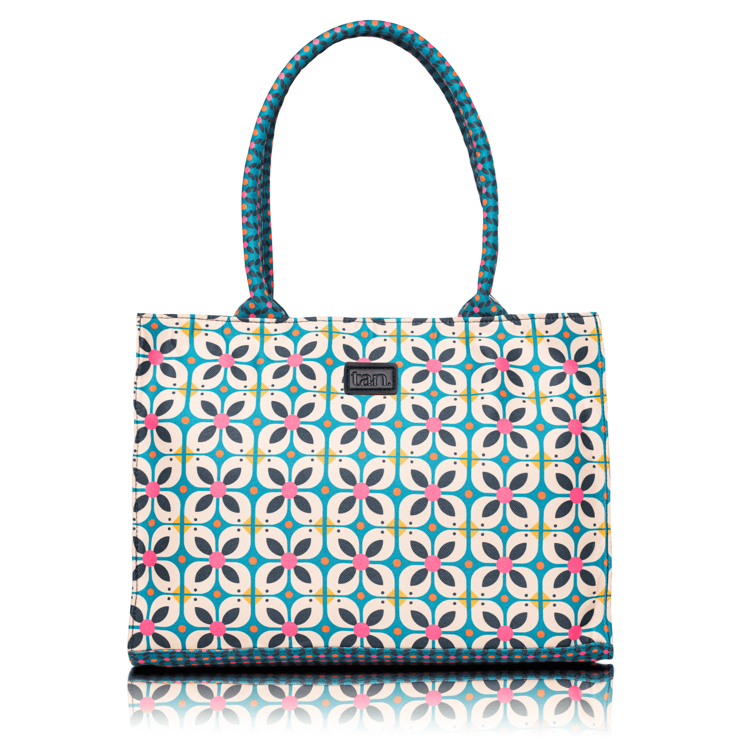 Canvas tote bag by tan. with a blue and pink geometric floral print and patterned top handles