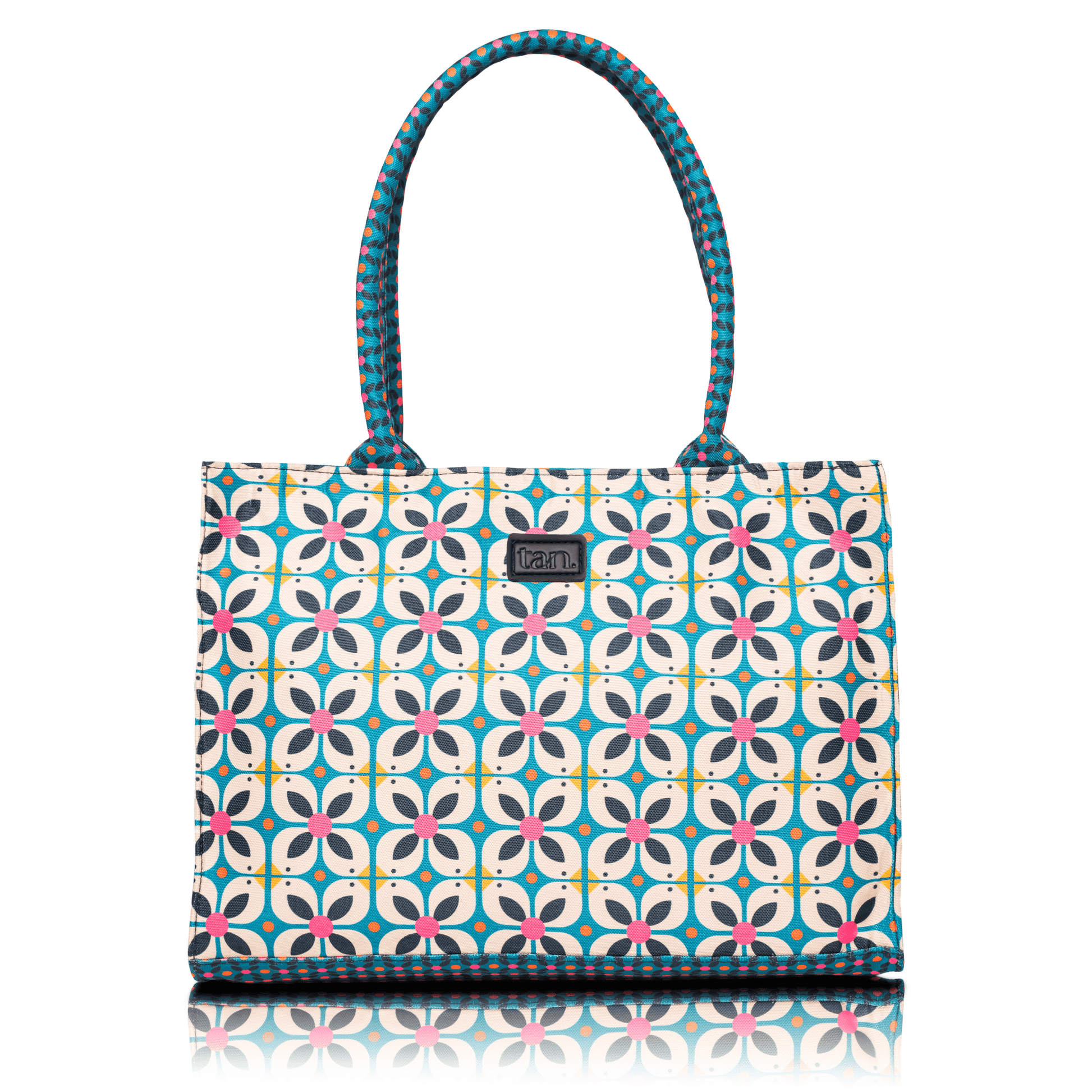Canvas tote bag by tan. with a blue and pink geometric floral print and patterned top handles