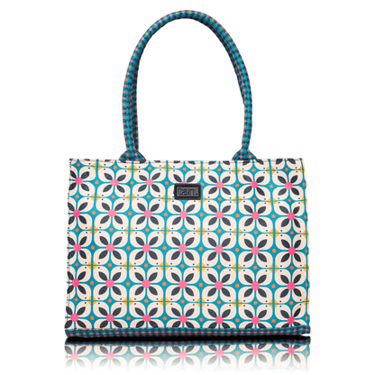 Canvas tote bag by tan. with a blue and pink geometric floral print and patterned top handles