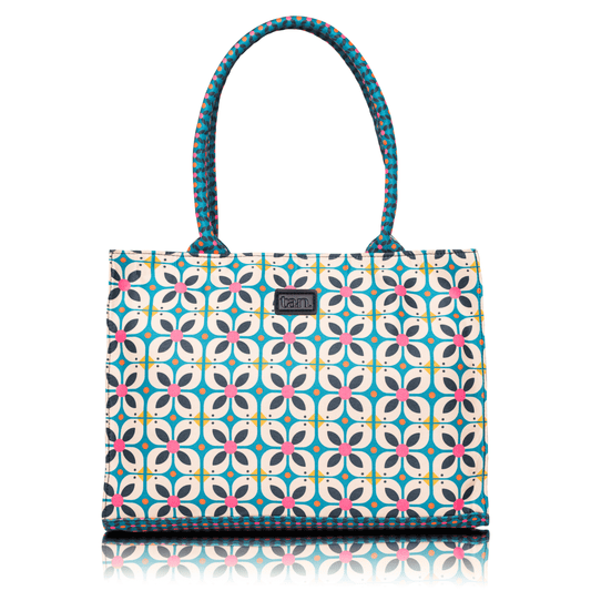 Canvas tote bag by tan. with a blue and pink geometric floral print and patterned top handles