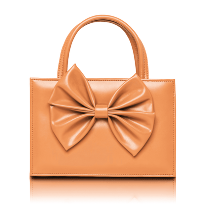 Small tan top handle handbag featuring a large decorative leather bow.