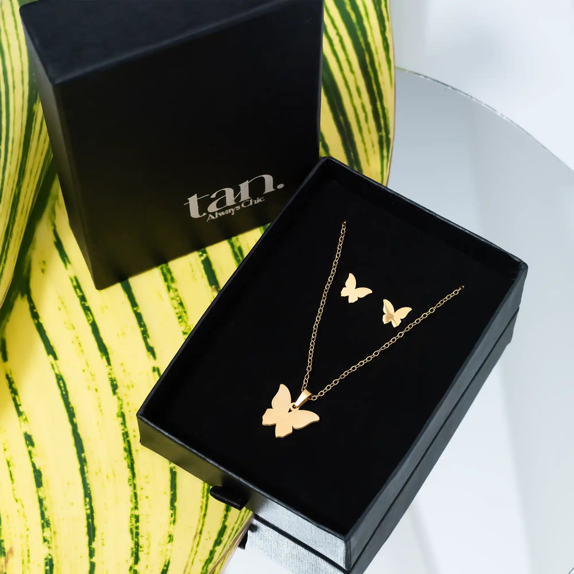 Gold butterfly jewelry set with necklace and matching stud earrings in a premium black gift box by tan.