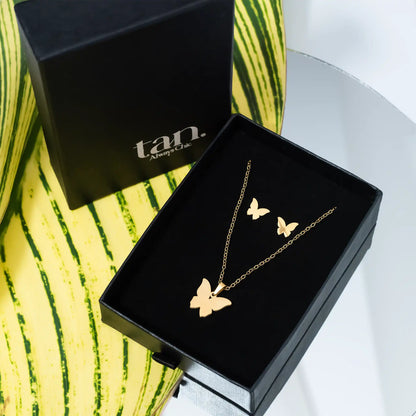 Gold butterfly jewelry set with necklace and matching stud earrings in a premium black gift box by tan.