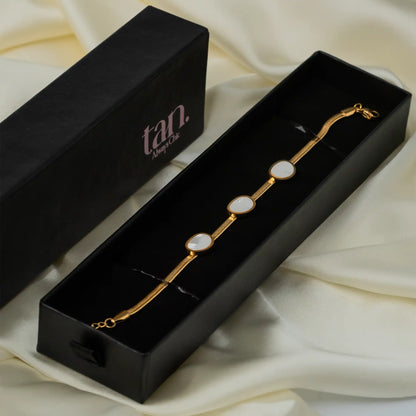 Gold snake chain bracelet with oval white shell insets in a black Tan gift box