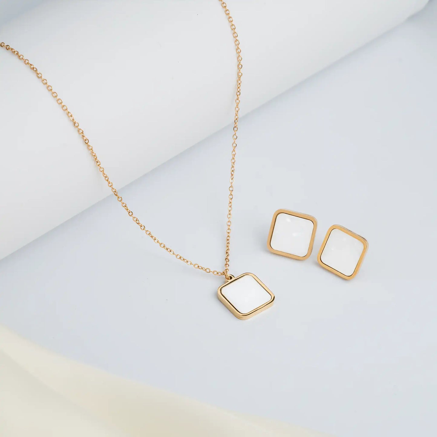 gold chain and white square pendant set with studs
