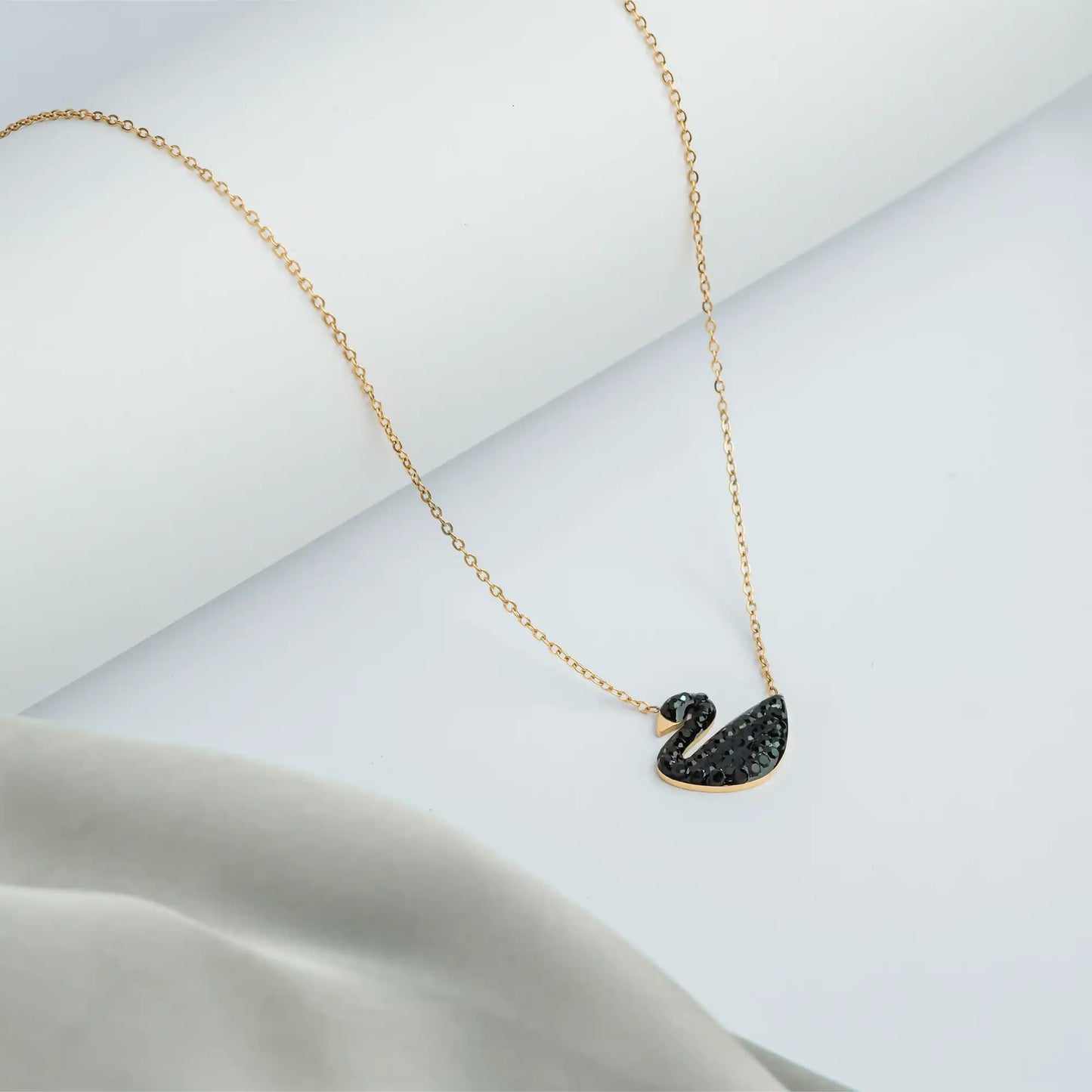 Gold chain necklace with a black crystal swan pendant.