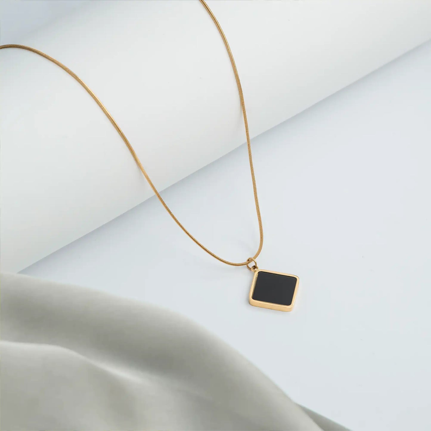 gold necklace with black pendant and delicate chain