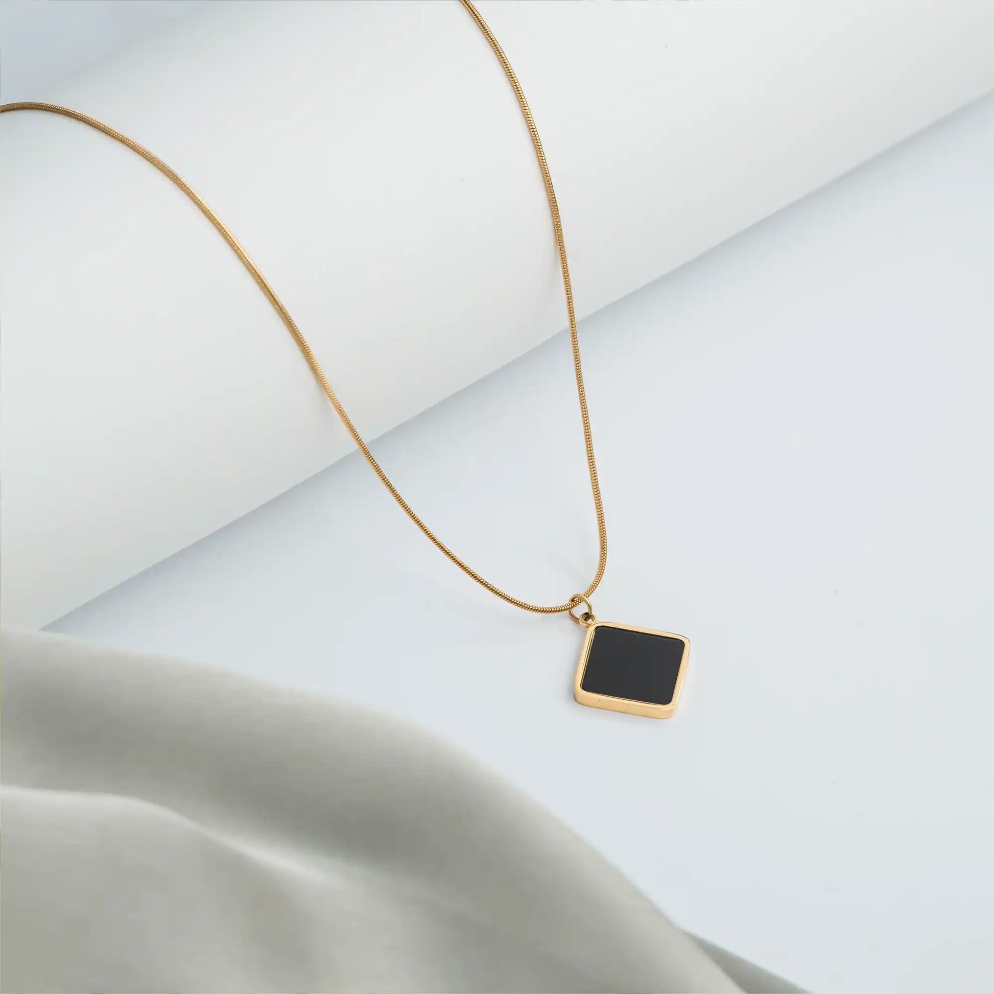 gold necklace with black pendant and delicate chain